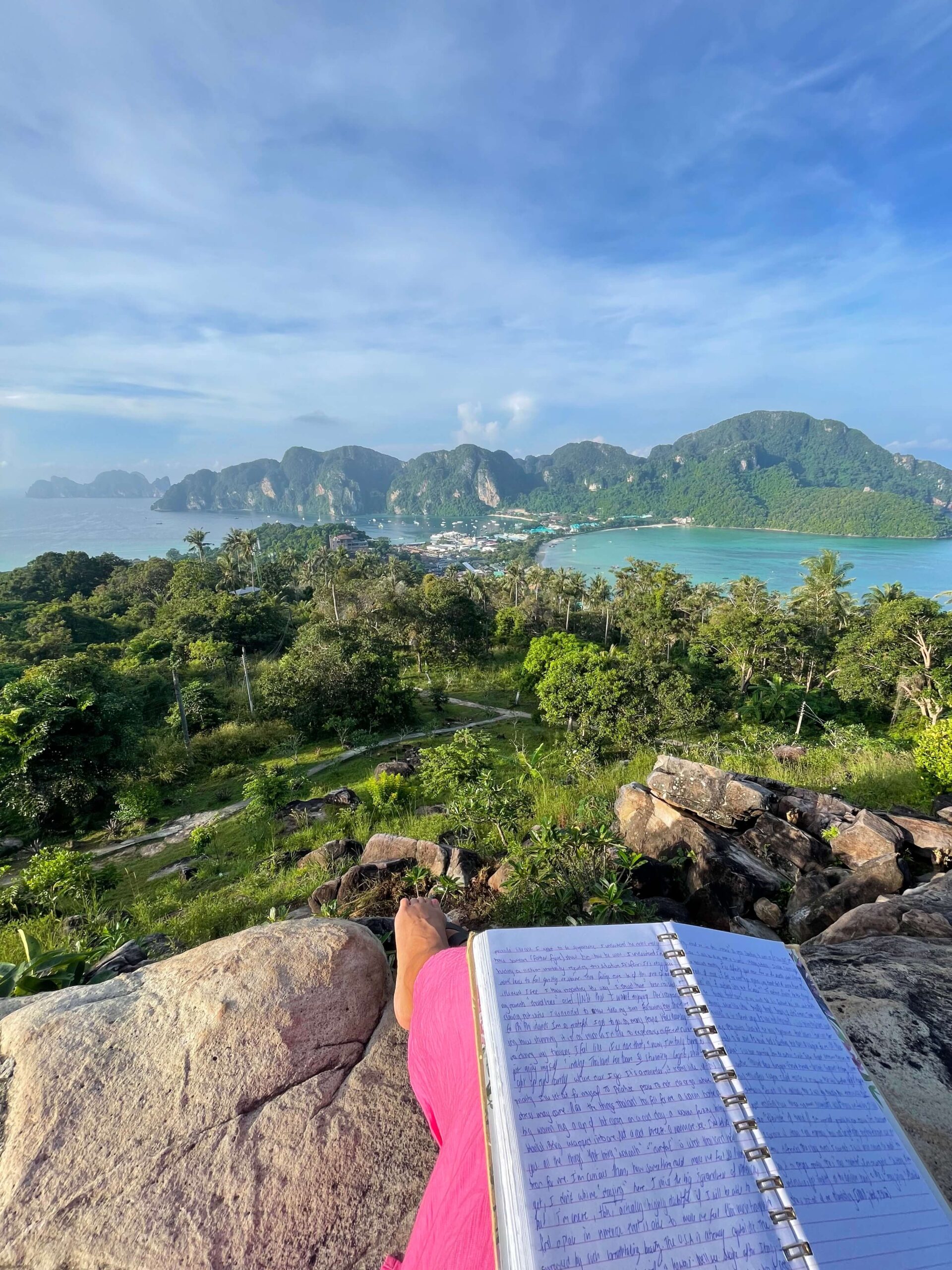 Me as a solo female traveler journaling in Phi Phi Island, Thailand at the top of viewpoint 2