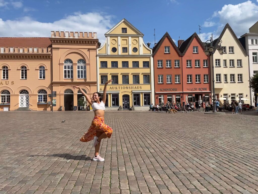 Me as a solo female traveler in Schwerin, Germany wearing a pink sneakers, orange floral dress