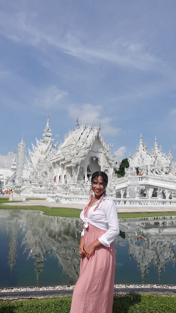 Solo female traveler standing by the white temple while visiting chiang rai thailand