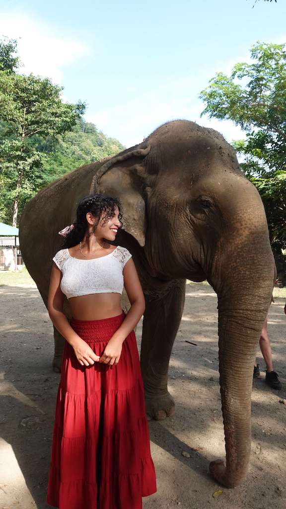 solo female traveler standing next to elephant while visiting elephant sanctuary in chiang mai thailand