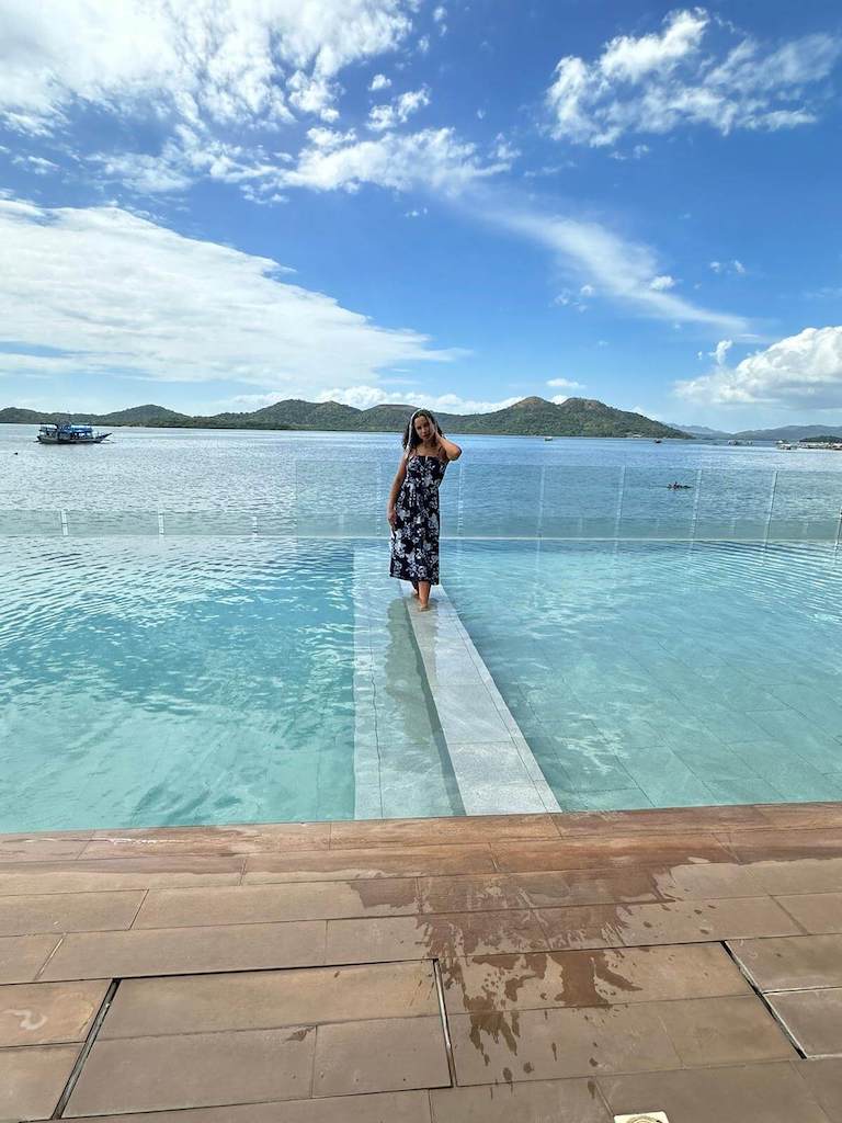 Solo female traveler standing in infinity pool at the Two Seasons Bayside Hotel in Coron Town, Philippines