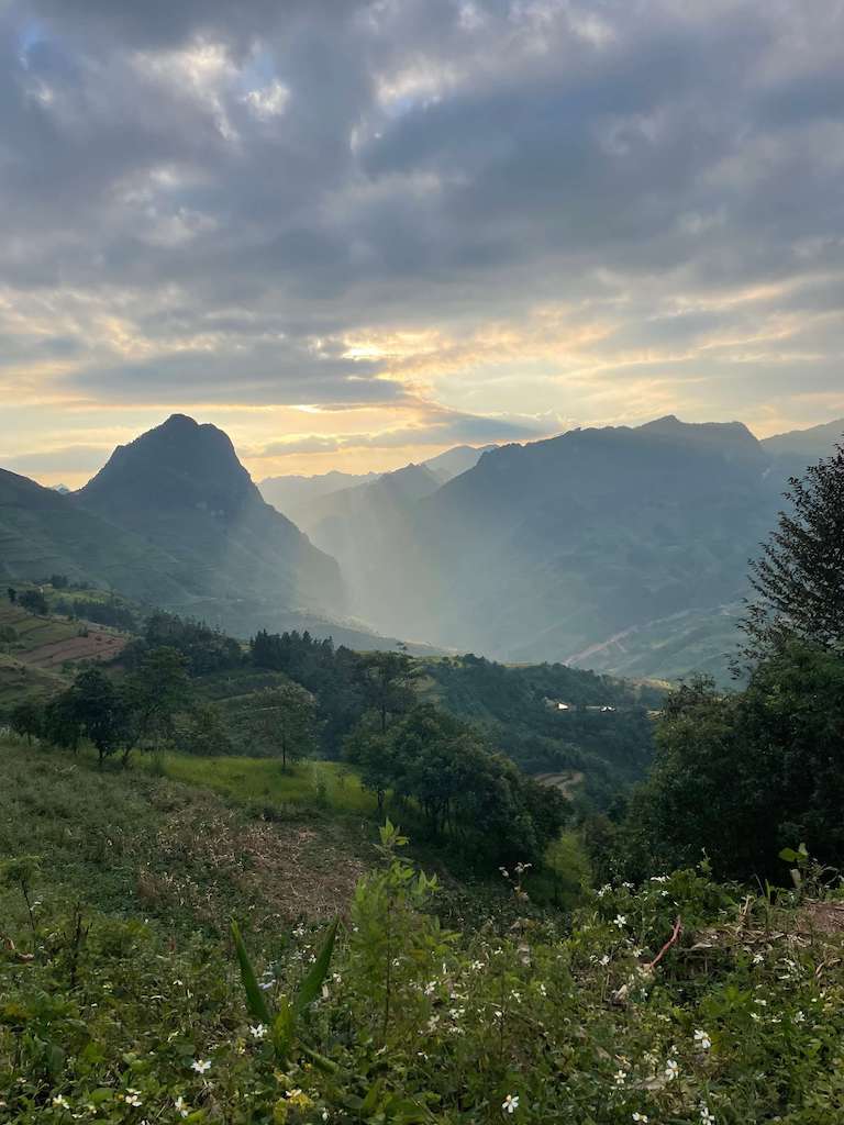 Sunset during Ha Giang Loop Tour, where sun's rays pierce through gray clouds