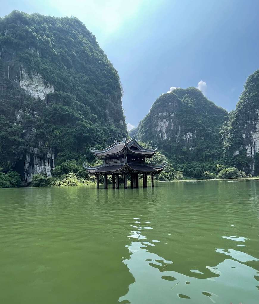 King Kong Temple in Ninh Binh Vietnam in front of towering lime stone cliffs decorated with luscious greenery