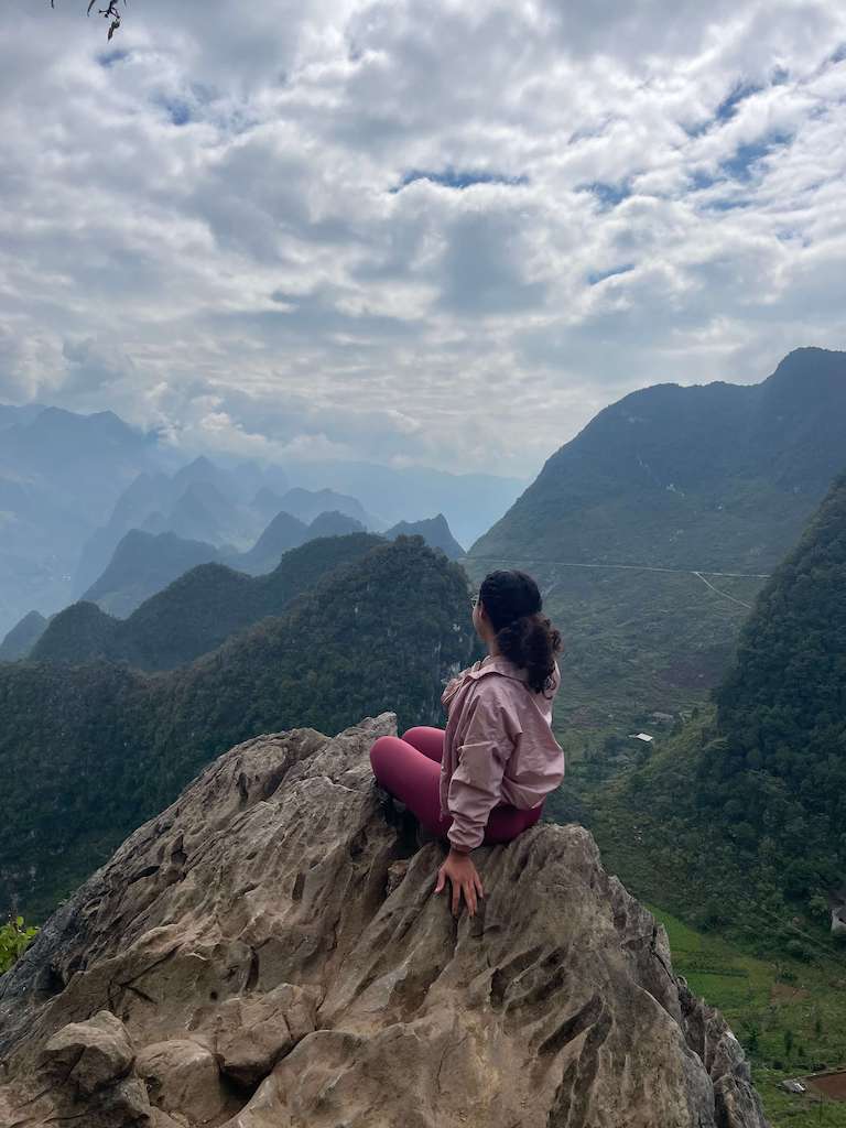 Solo female traveler sitting on a mountain top during her Ha Giang Loop Tour